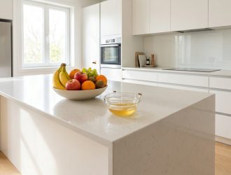 Des moucherons volent autour d'un bol de fruits et d'un piège à vinaigre sur un îlot de cuisine moderne.